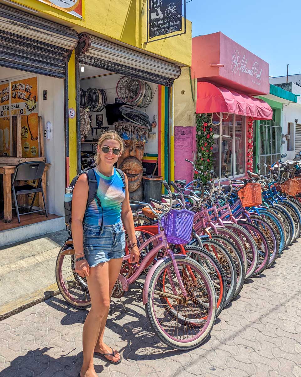 Bailey standing beside rental bikes on Isla Mujeres, Mexico