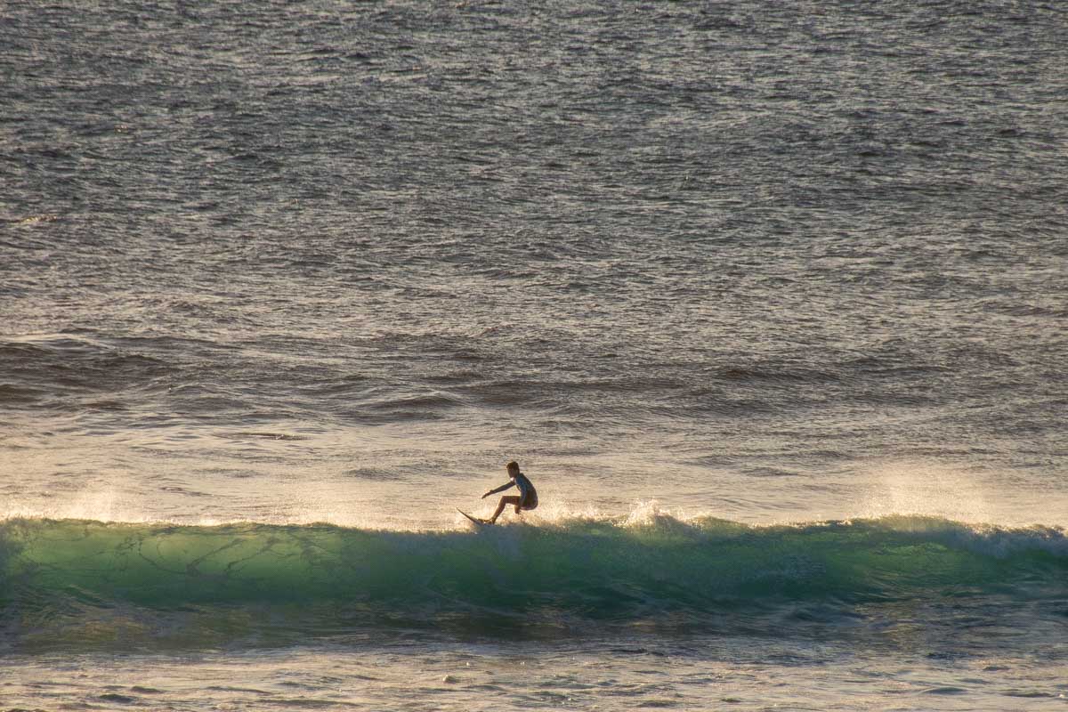 A surfer at Surfers Point at sunset in Margaret River, WA