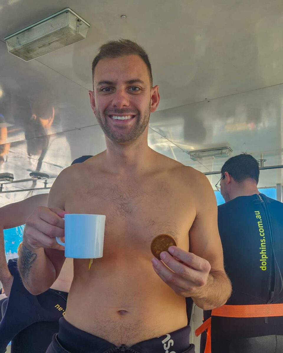 Daniel with a coffee and biscuit on the dolphin swim in Perth