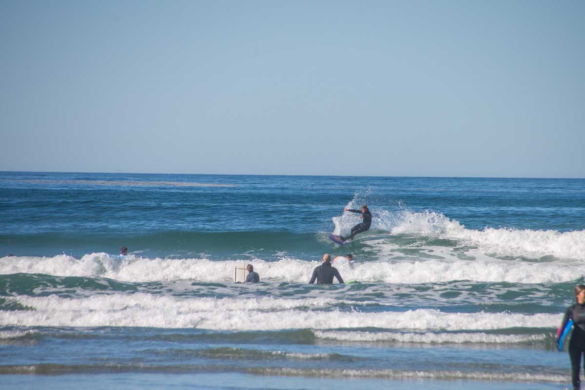 A surfer at Cox Bay Beach surfing a small wave