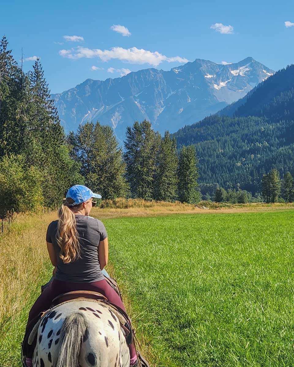Bailey rides a horse through a field in Pemberton, BC
