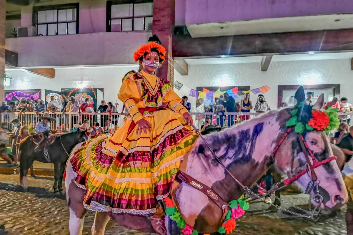 A girl rides a horse dressed up during Day of the Dead in Puerto Vallarta