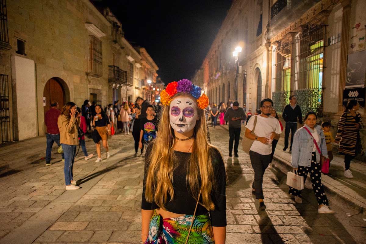Bailey stands in the middle of a street in Oaxaca with her face painted during Day of the Dead