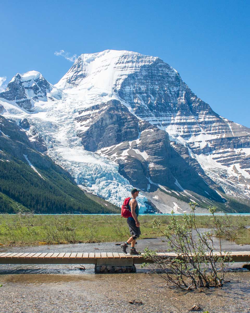 A hiker walks across a wooden bridge in Mount Robson Provincial Park, Canada