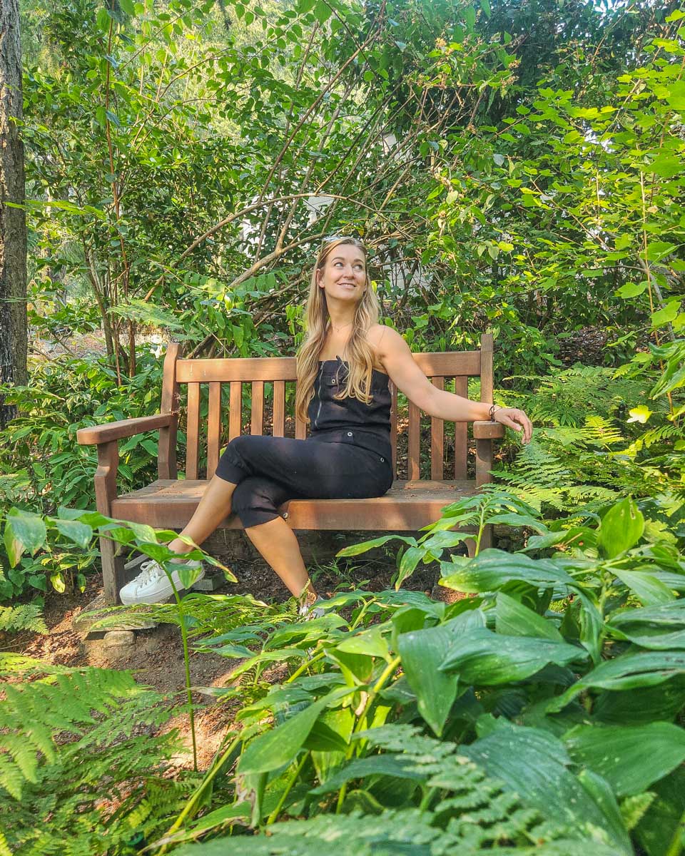 Bailey sits on a bench surounded by greenery at The Butchart Gardens