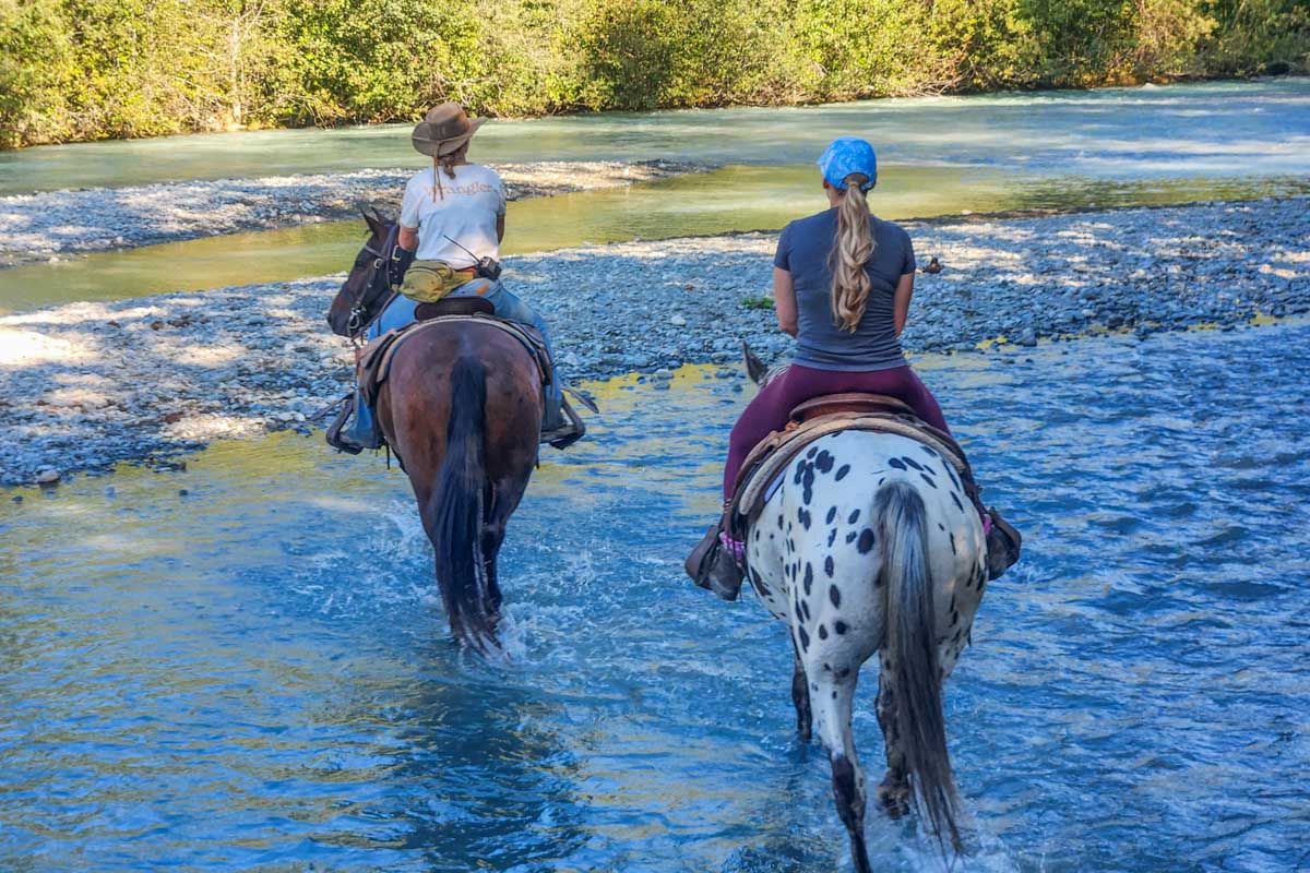 Bailey and our guide cross a river on a horseback riding tour in Pemberton BC