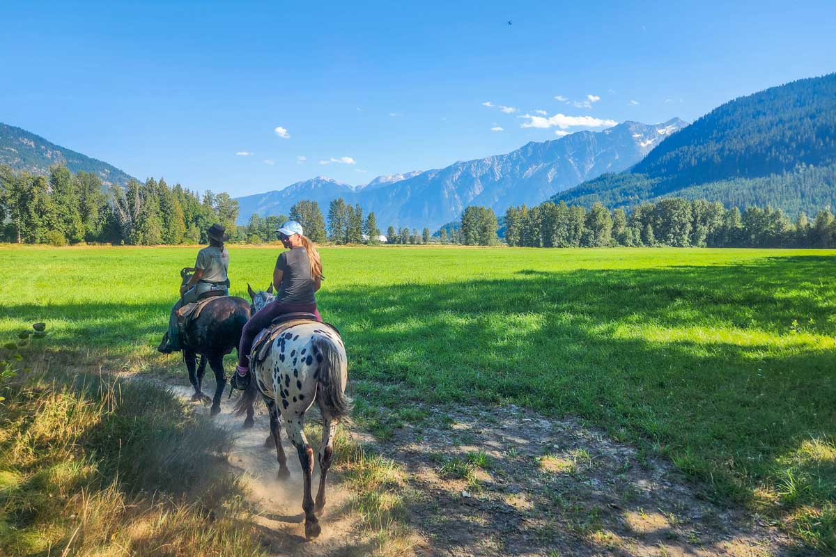 Bailey rides her horse through a field with a mountain backdrop in Pemberton BC