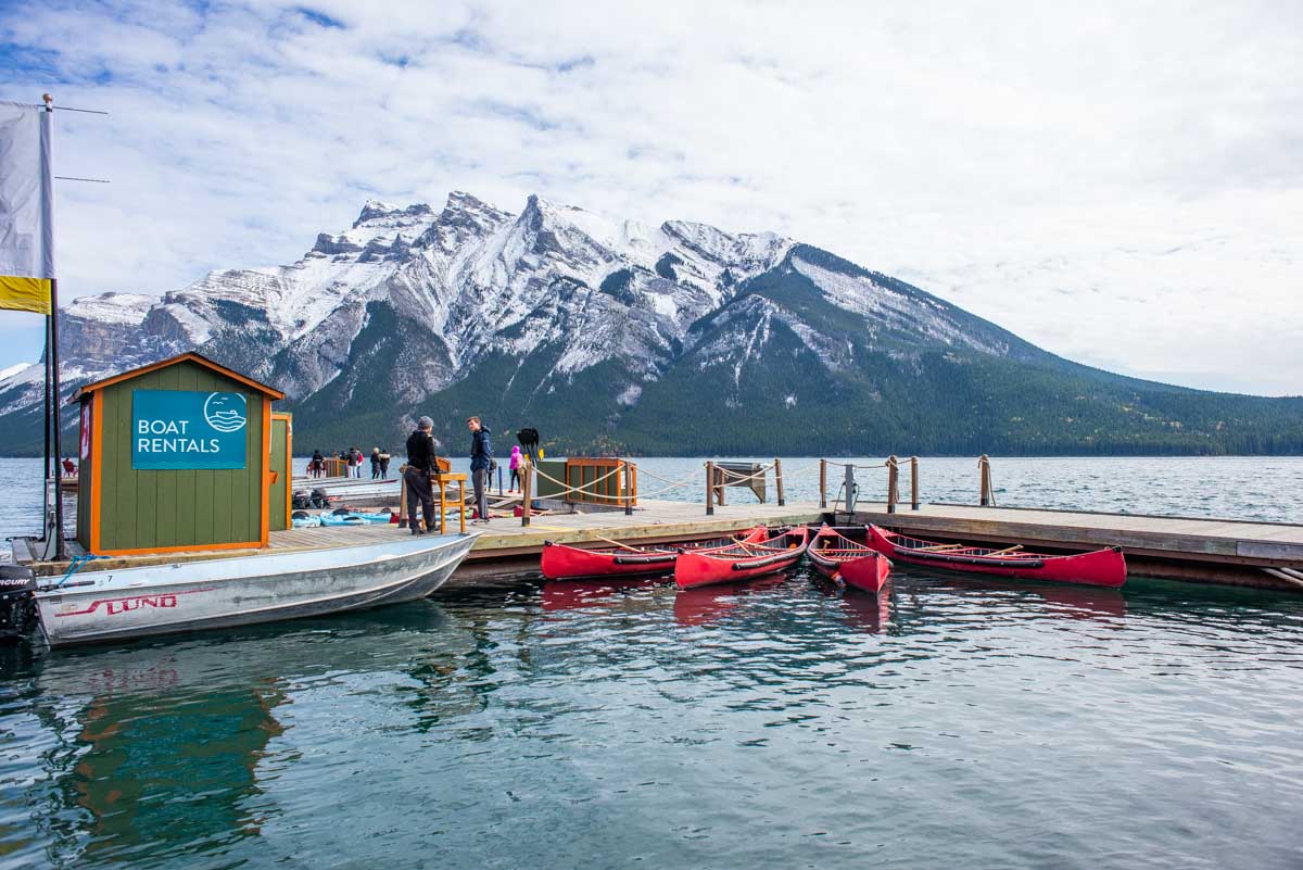 the dock at Lake Minnewanka with canoes there and mountains in the back ground