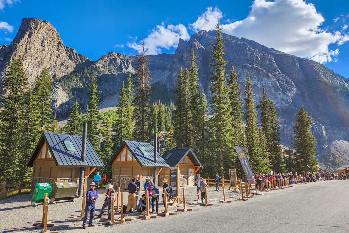 People line up at the Moraine Lake bus stop for the bus