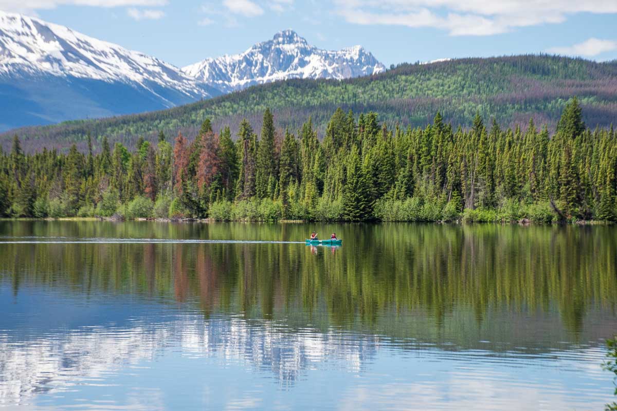 Two people canoe with mountain backdrop at Pyramid Lake in Jasper National Park, Canada