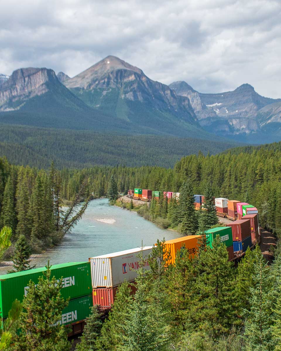 A train passes Morant's Curve in summer along the Bow Valley Parkway