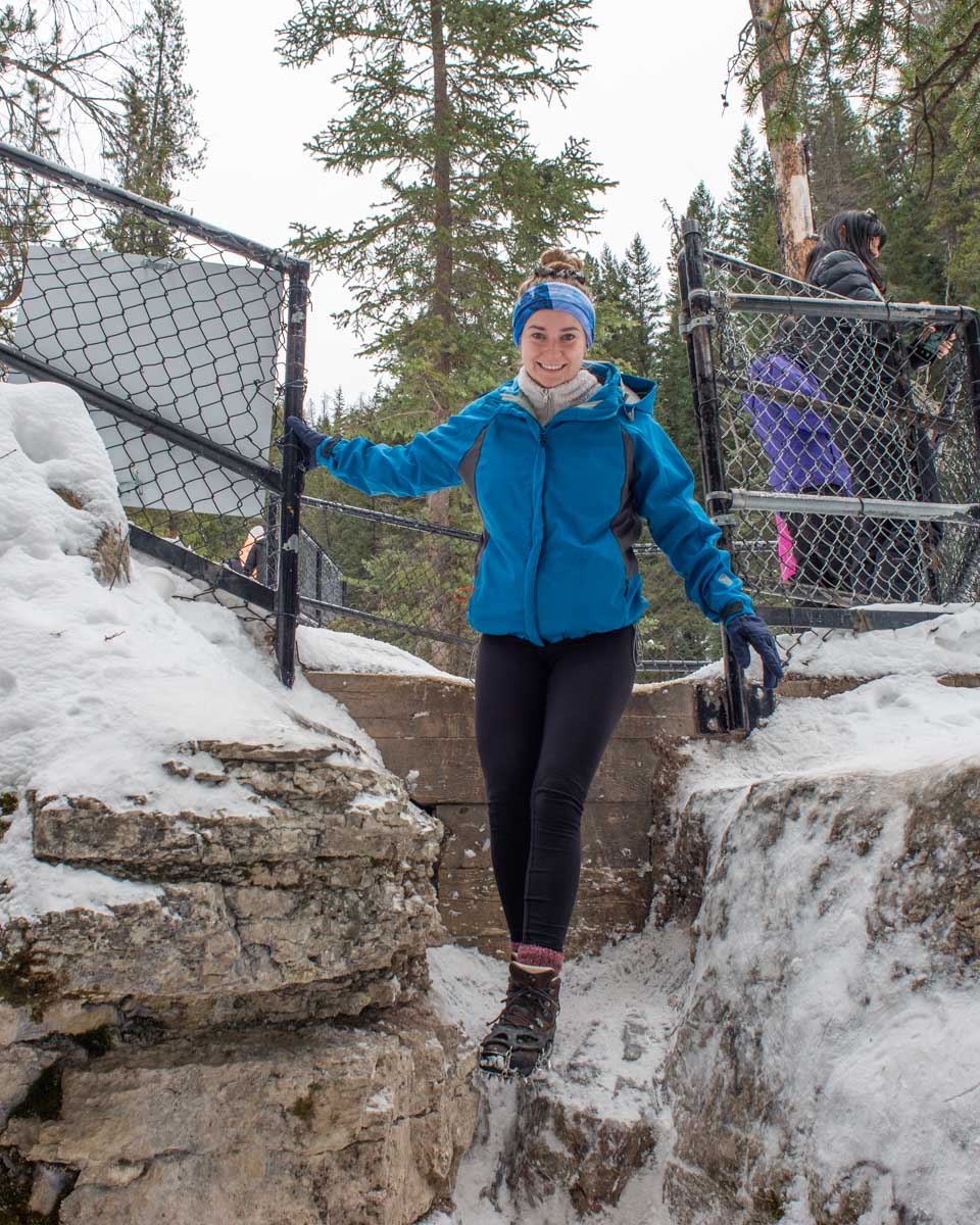 Bailey steps down onto the ice and the entry in Maligne Canyon in winter in Jasper