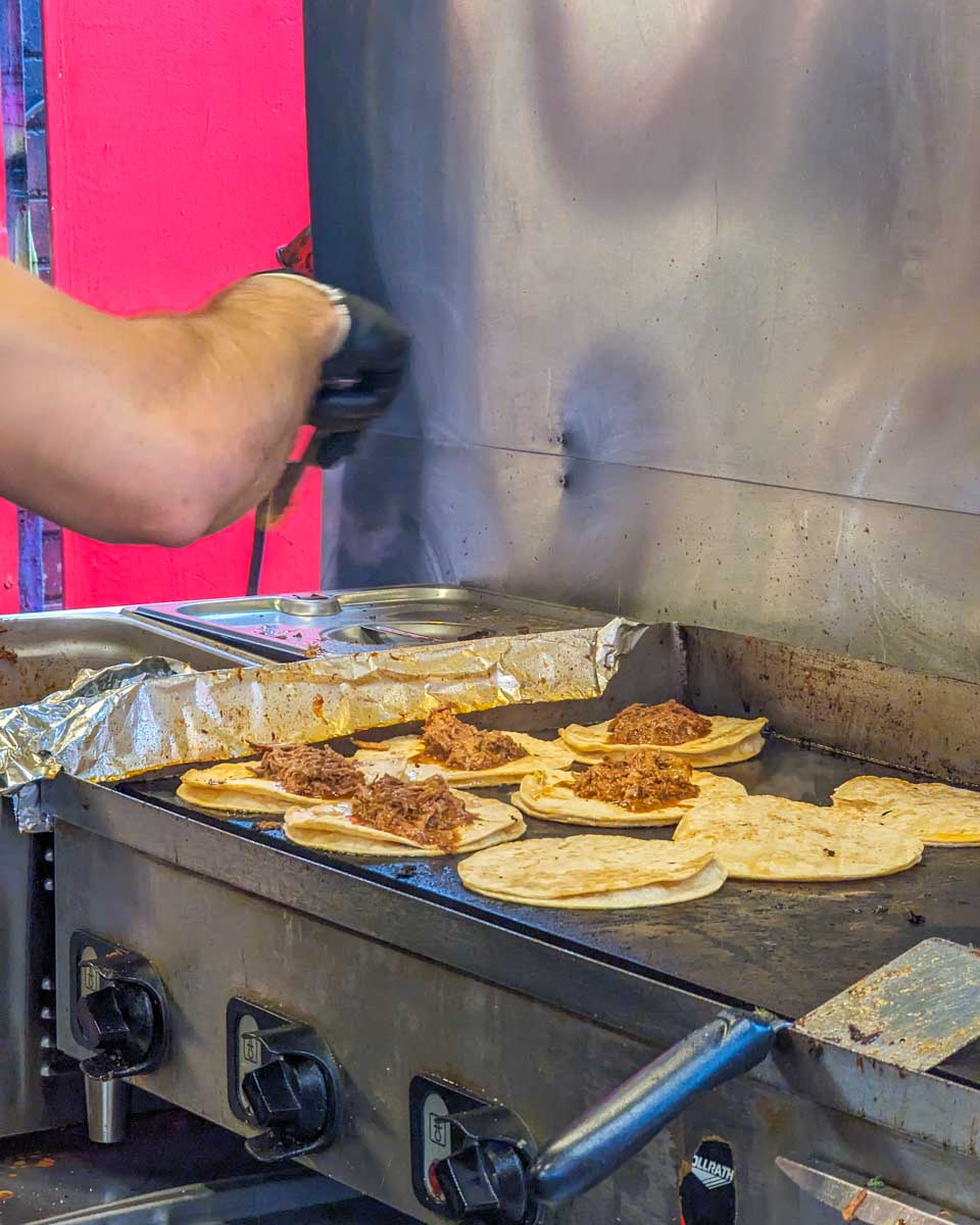 Tacos cook on a grill on a food tour in Toronto