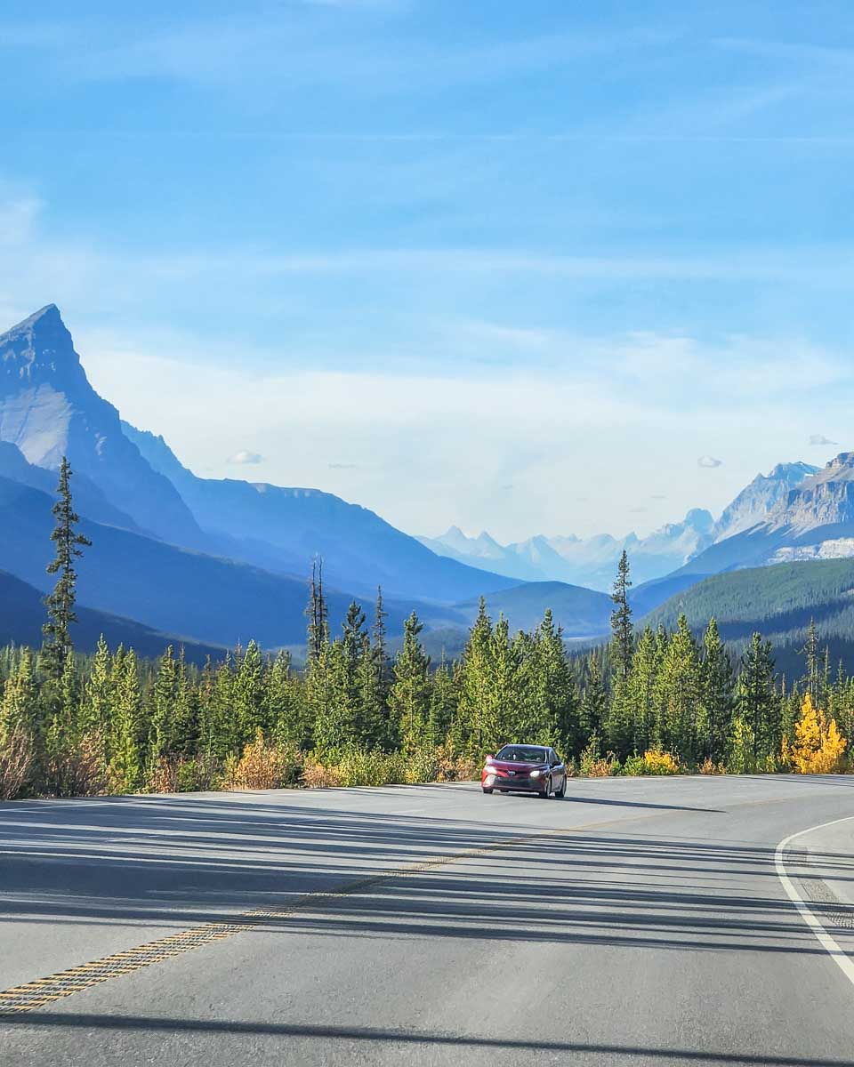 a car drives down the Scenic road down the Icefields Parkway in Canada