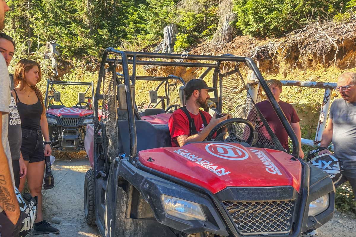 A guide shows a group of people how to drive an ATV on a tour in Whistler, BC