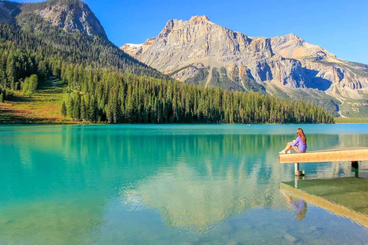 A lady sits on the dock at Emerald Lake in Yoho National Park, Canada