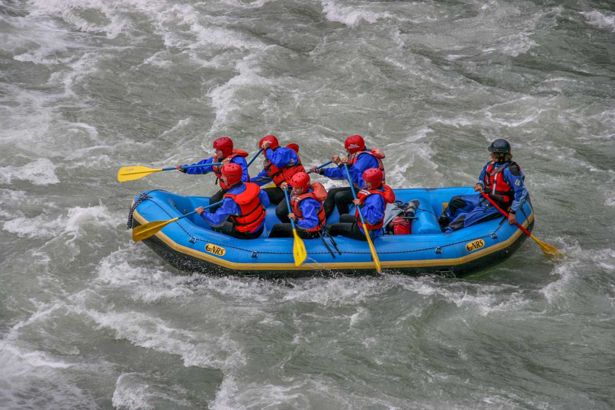 From above a group of people float through rapids while white water rafting in Banff