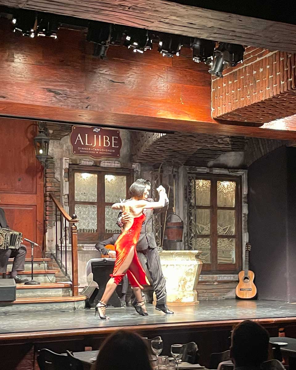 A dancer in a red dress does tango with her partner during a tango show in Buenos Aires