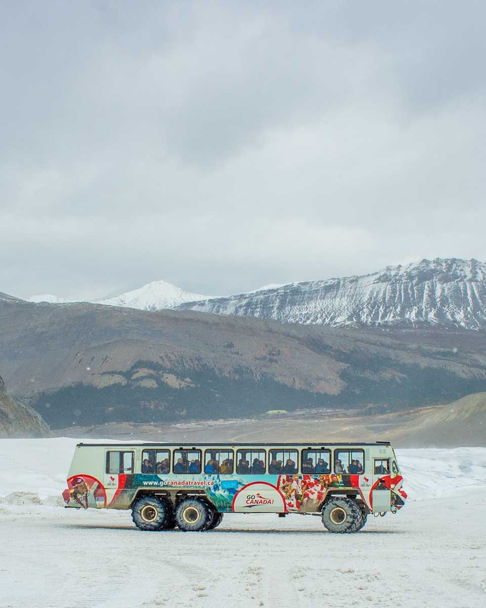 the ice explorer athabasca glacier bus drives on the glacier with a mountain backdrop