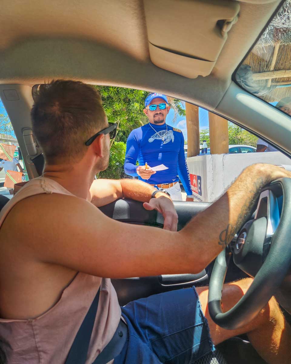 Daniel pays for parking in our rental car in Mexico at Akumal Beach