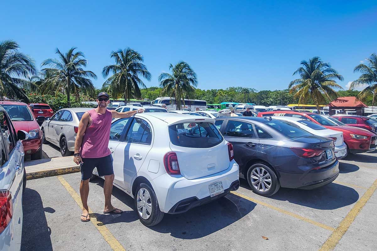 Daniel poses for a photo with our rental car at the Tulum Ruins parking lot in Tulum, Mexico