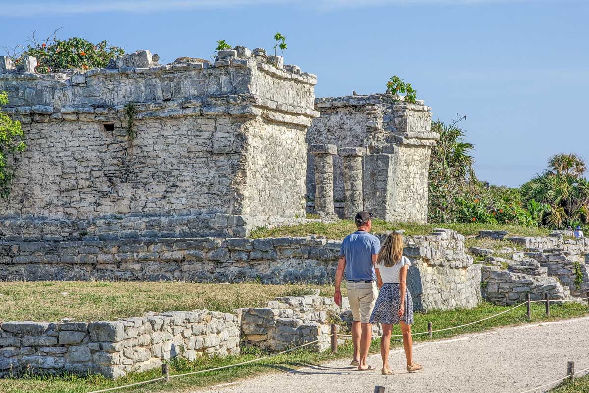 Two people walk the Tulum Ruins site