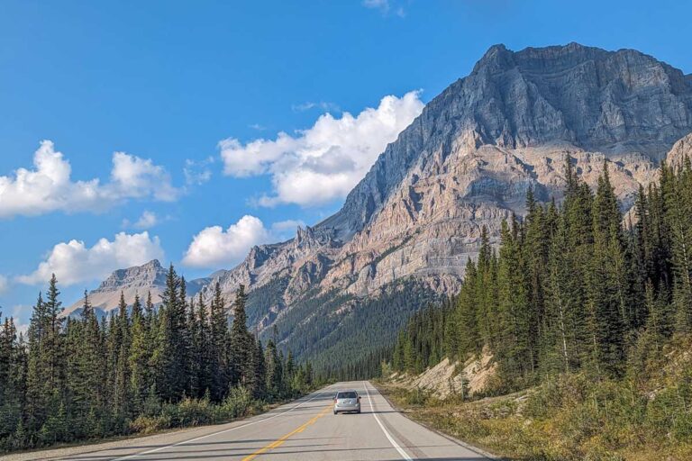 A car drives along the Icefields Parkway in Banff National Park