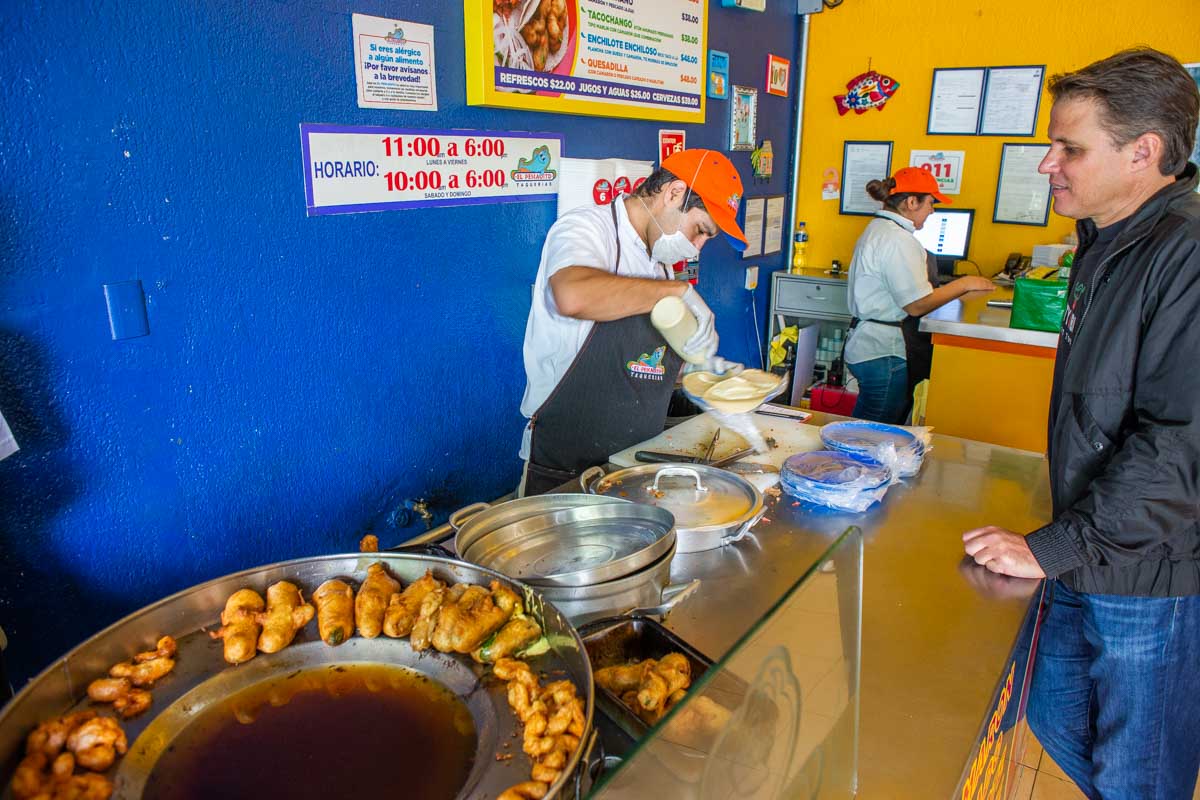A man prepares seafood tacos at a taco restaurant in Mexico City on a taco tour