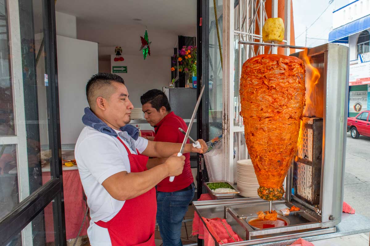 Al pastor tacos being cooked by a taco chef