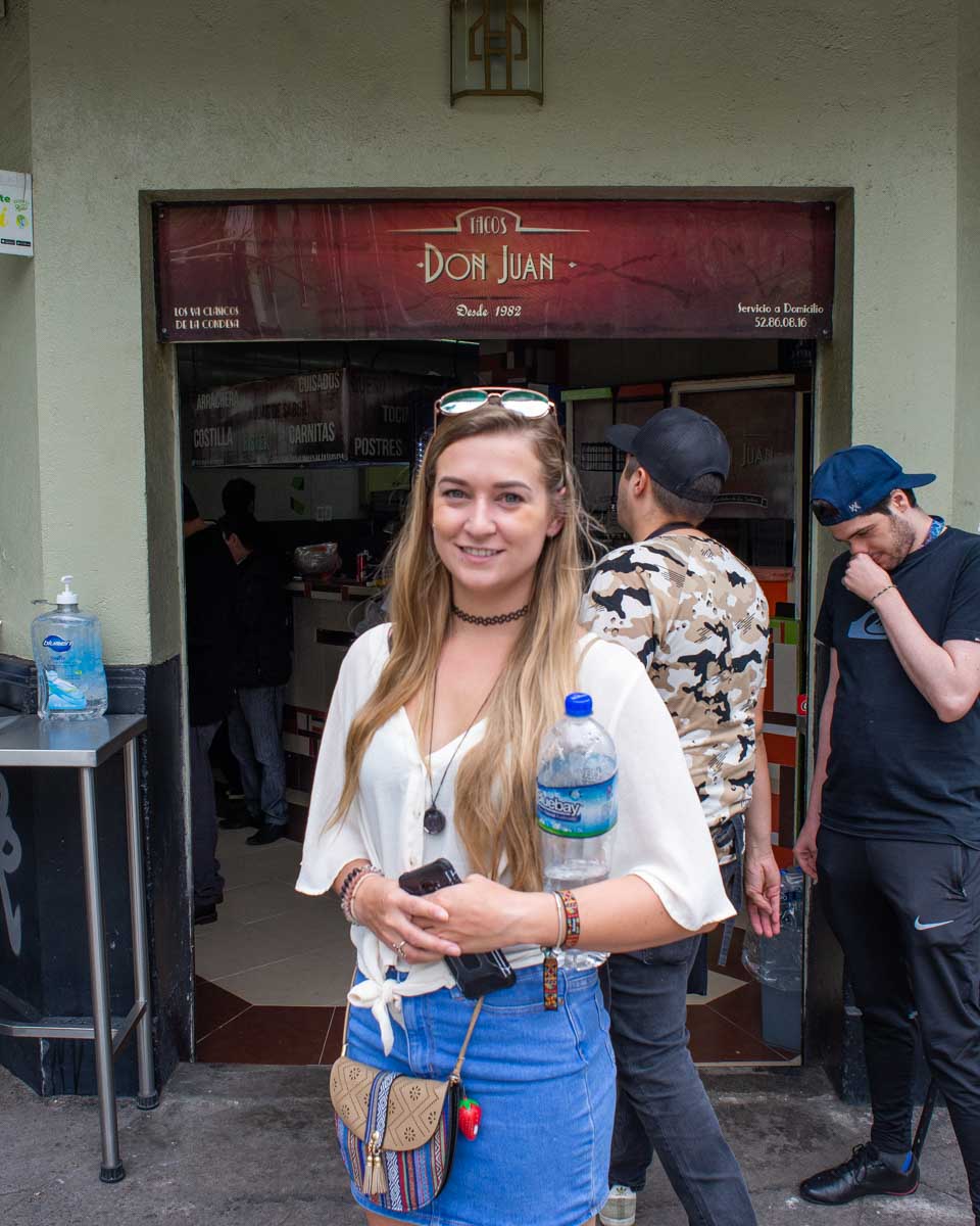 Bailey stands out the front of a taco stand in Mexico City on a taco tour