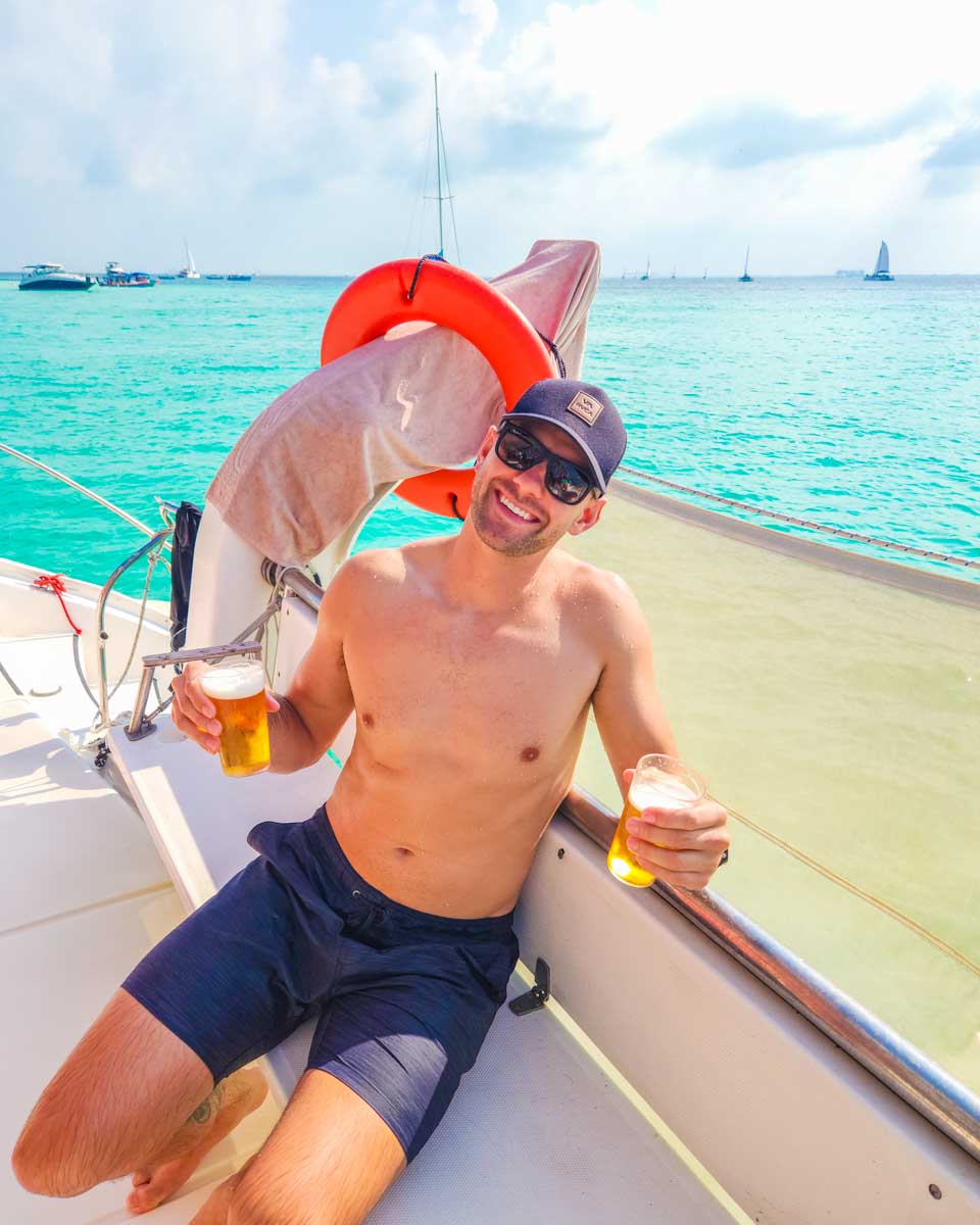 Daniel poses for a photo with a drink in his hand on a Catamaran cruise in Cancun