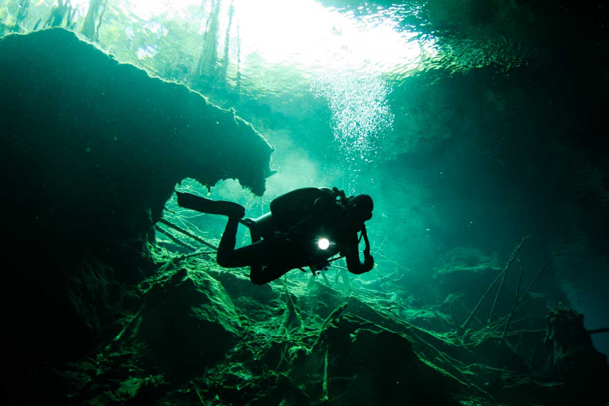 A man dives in a cenote in Tulum, Mexico