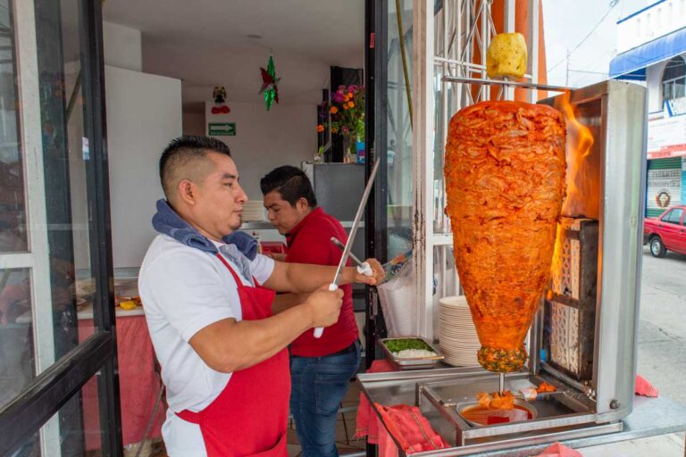 Al pastor tacos being cooked by a taco chef
