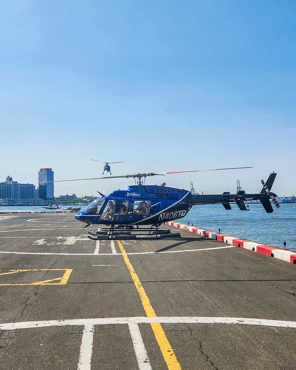 A helicopter ready to take off in NYC and another helicopter coming into land at the Manhattan Heli Port