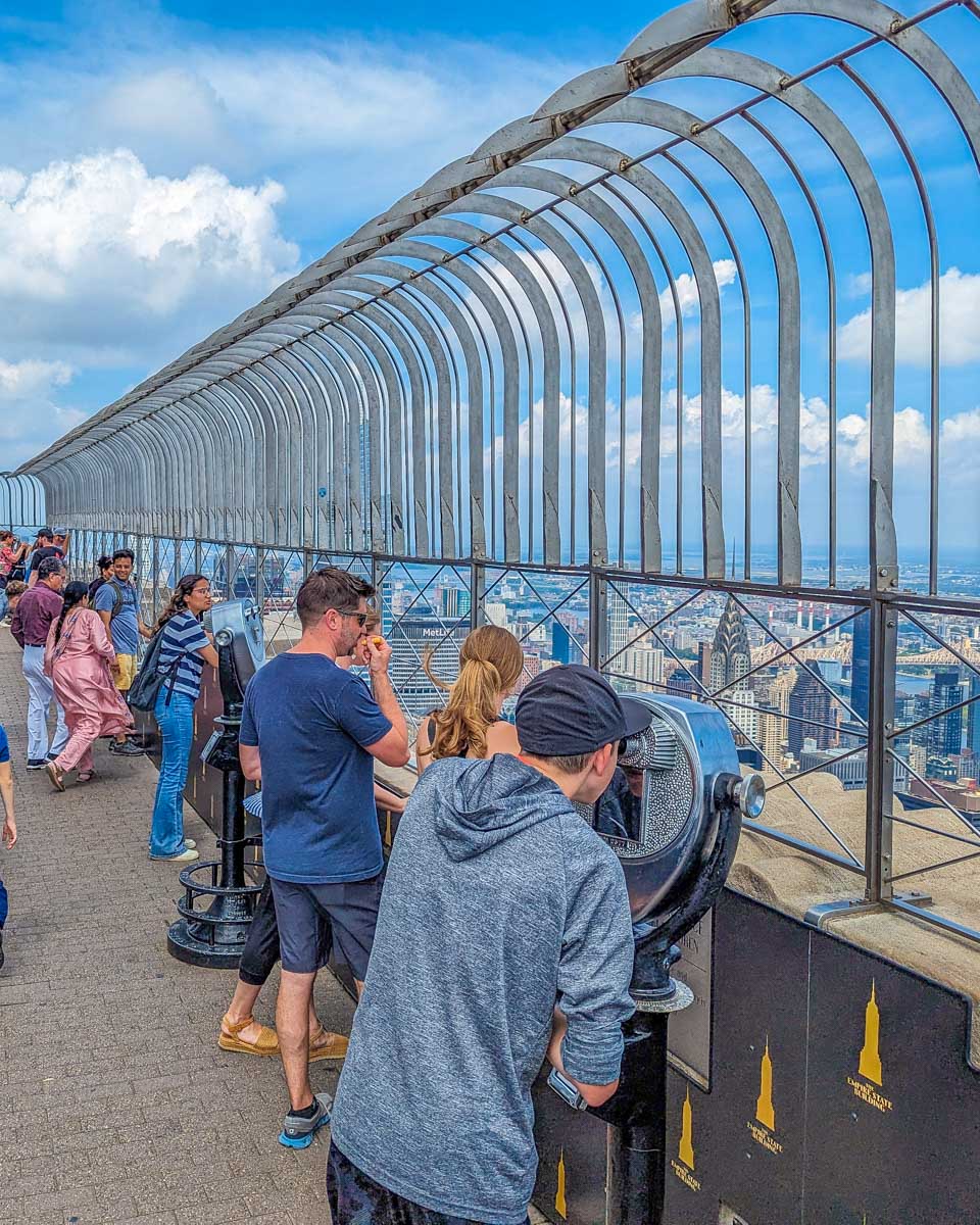 A tourists looks through binoculars at the empire State building in NYC