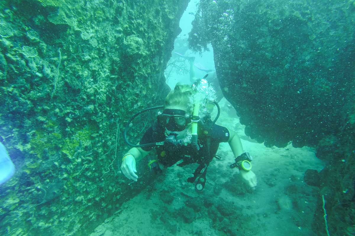 Bailey scuba dives through a small rock cave in Puerto Vallarta Mexico