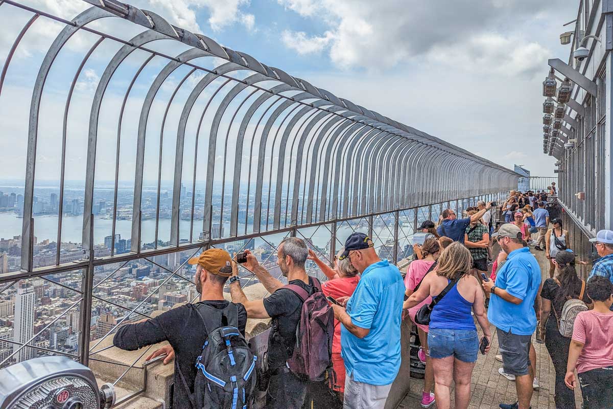 Crowd of toursits enjoy the view from the 86th Floor Observatory in New York at the Empire State Building in NYC