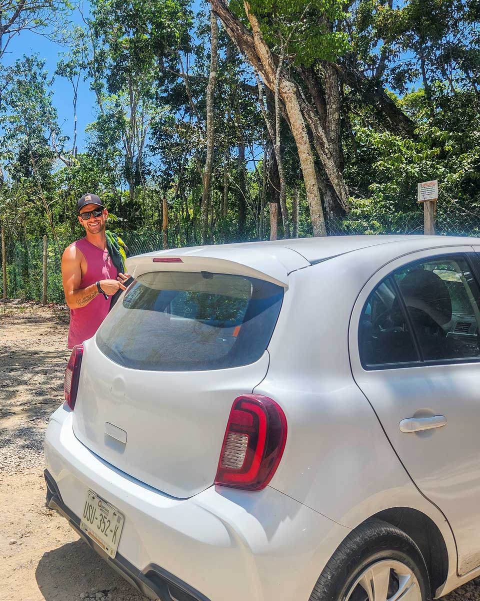 Daniel poses for a photo with our rental car at a cenote in Puerto Vallarta, Mexico