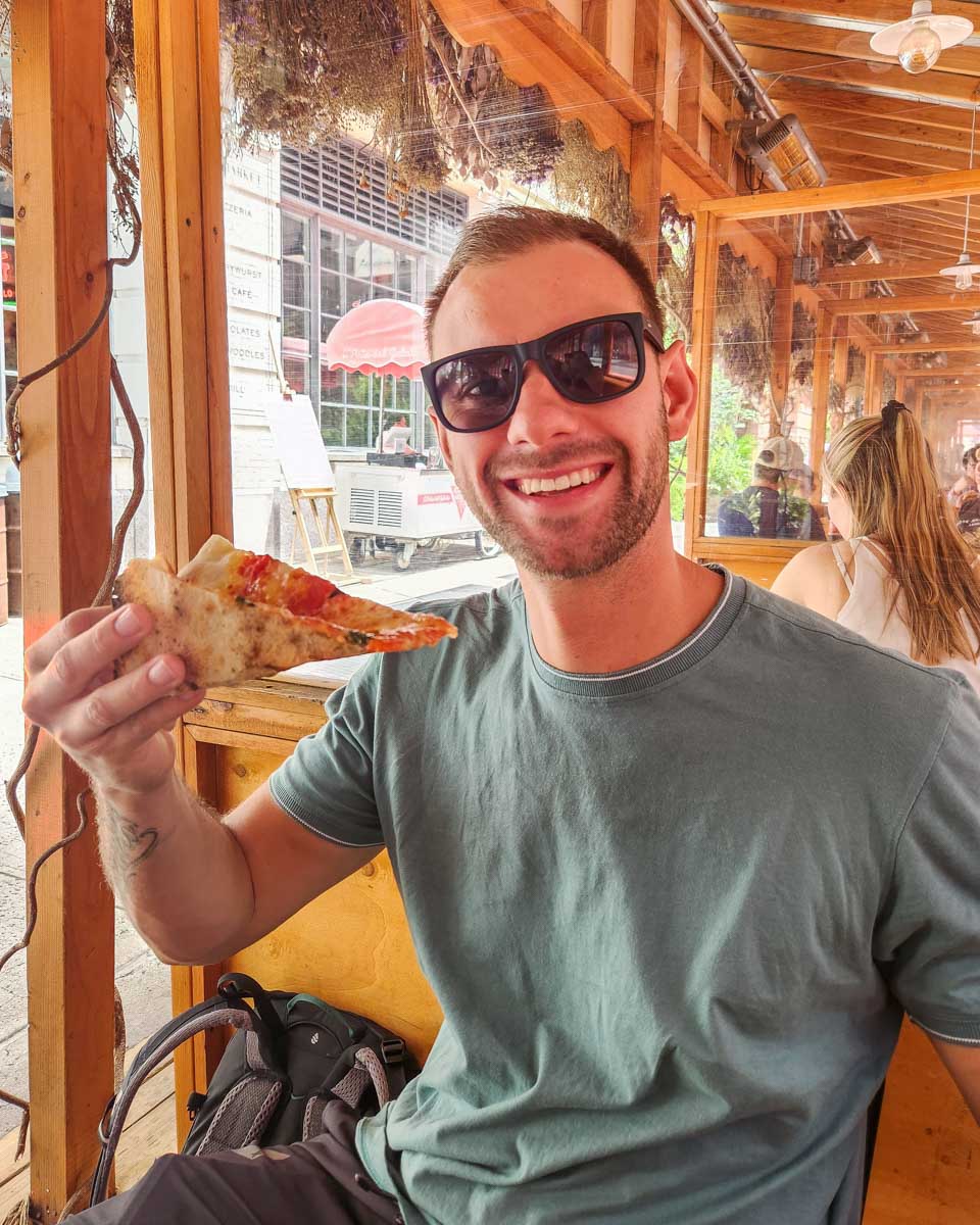 Daniel with his pizza at the Chelsea Market on our food tour
