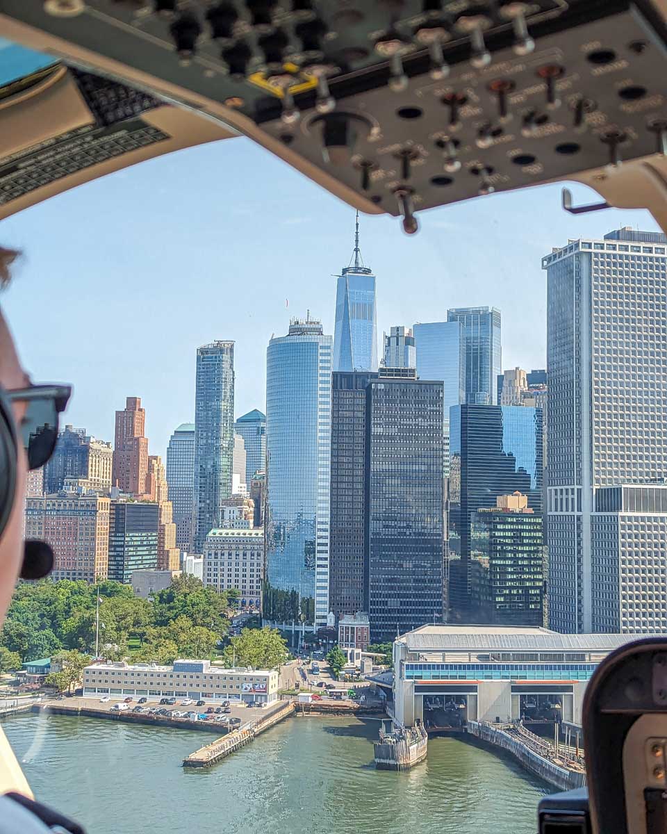 Pilot flies a helicopter with views of New York City from the Manhattan Heliport