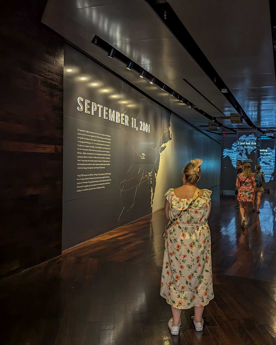 A lady reads a sign at the very begining on the 911 Museum walkway that talks about the attack