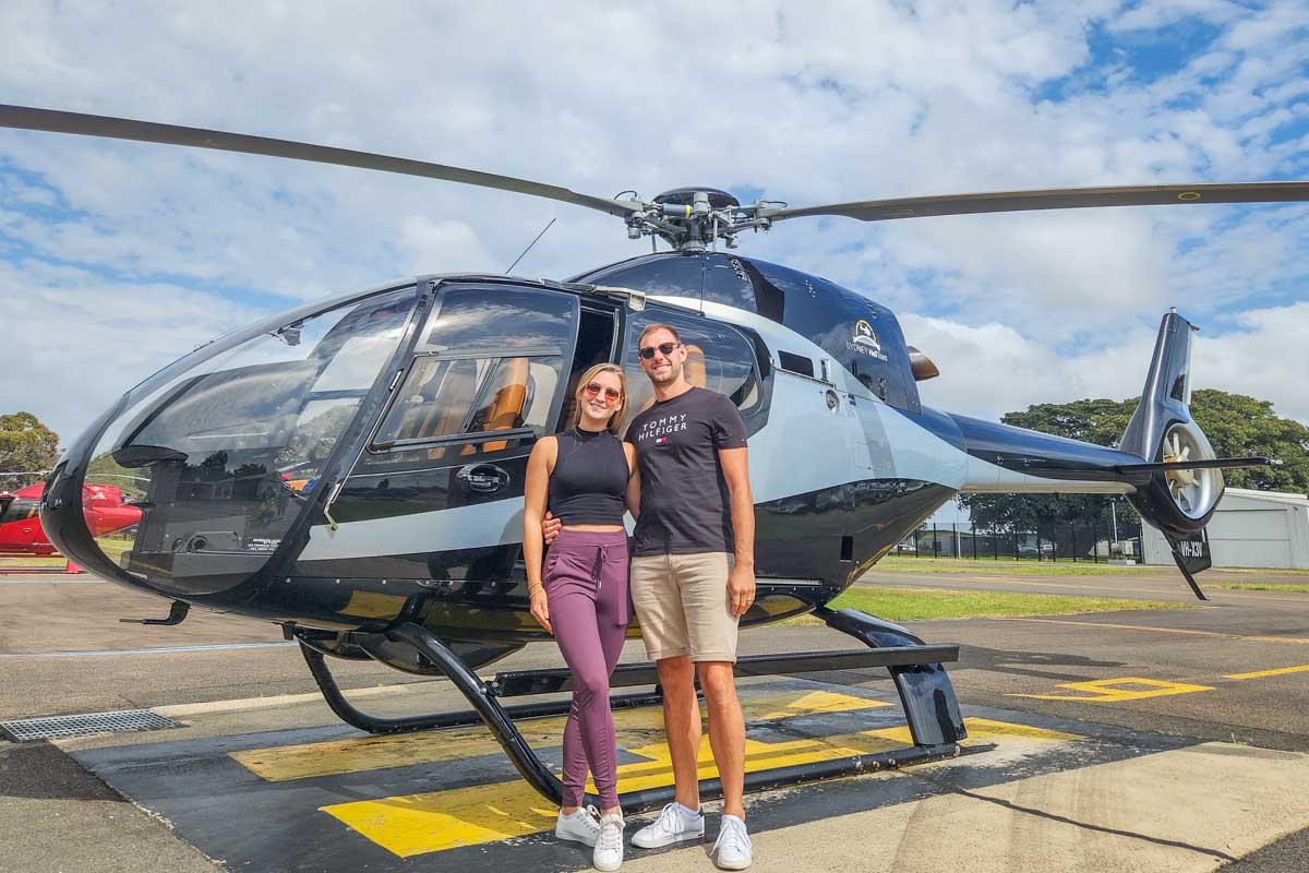 Daniel and Bailey pose for a photo in front of their helicopter tour in Sydney Australia