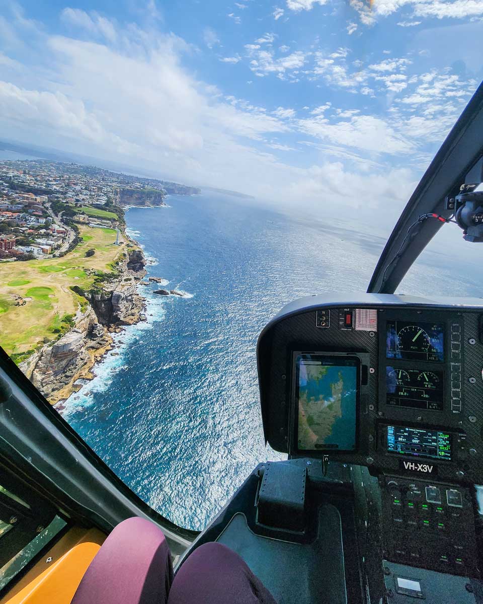 View out the front of a helicopter looking down at the coastline of Sydney, Australia