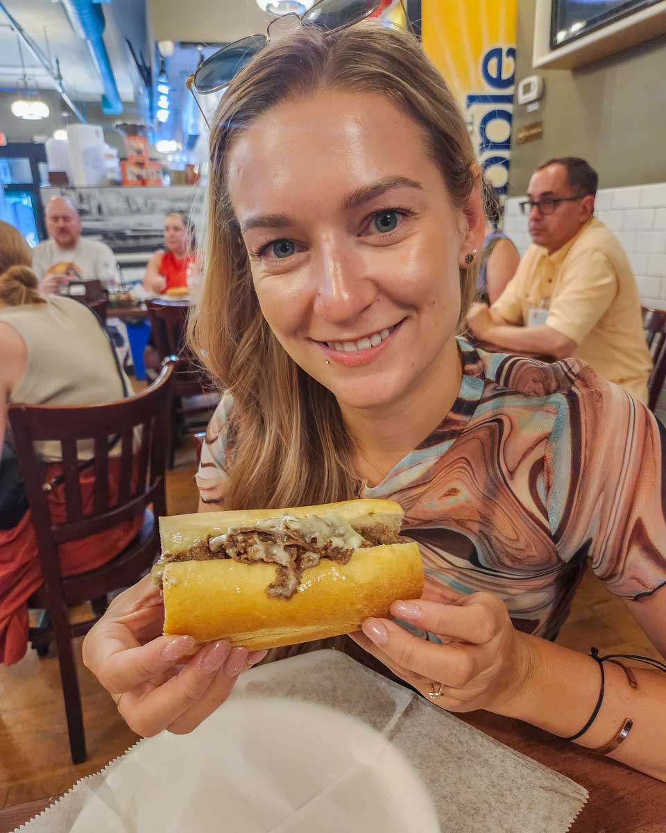 Bailey poses for a photo with a philly cheese steak we tried on our food tour