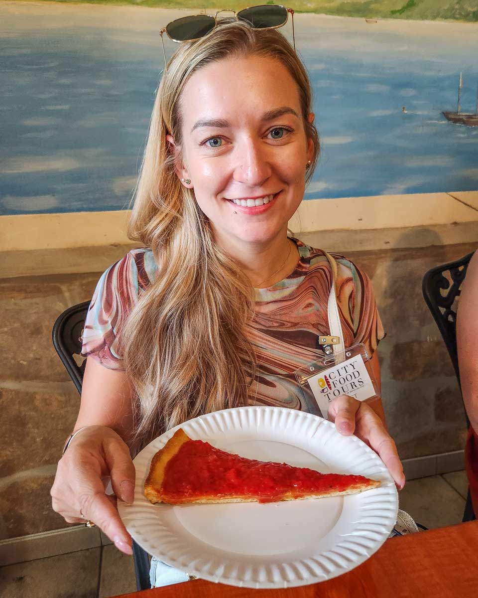 Bailey with a slice of Tomato Pie that we tried on a food tour around Philadelphia, US