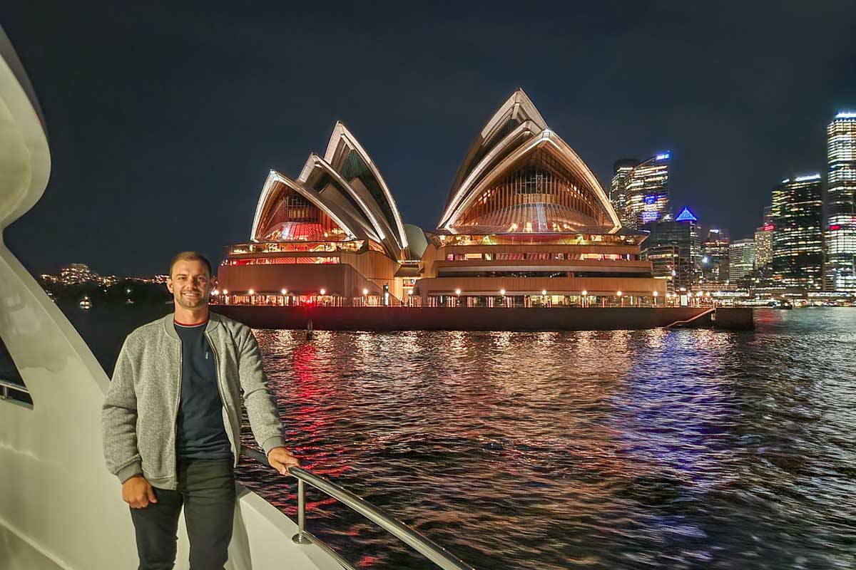 Daniel poses for a photo on a dinner cruise with the Sydney Harbour Bridge