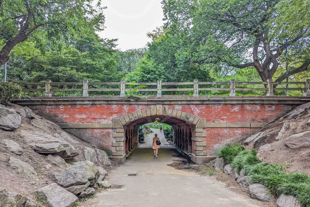 A lady walks under a bridge in Central Park, NYC