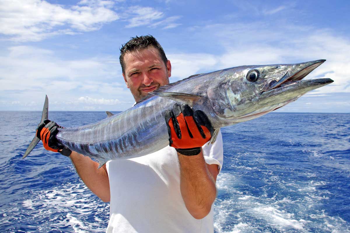 A man holds a large spanish Mackeral on a fishing tour in Puerto Vallarta