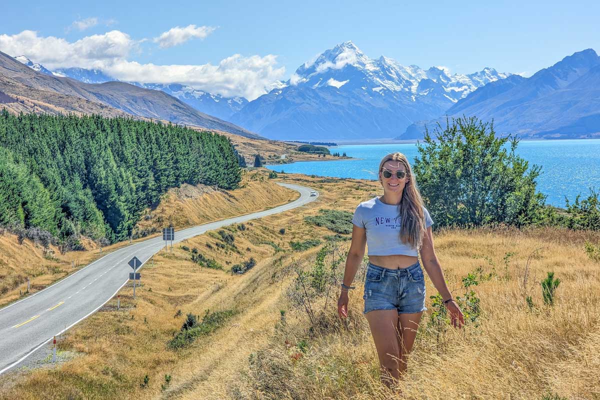 Bailey stands at a roadside viewpoint with Mount Cook in the background.
