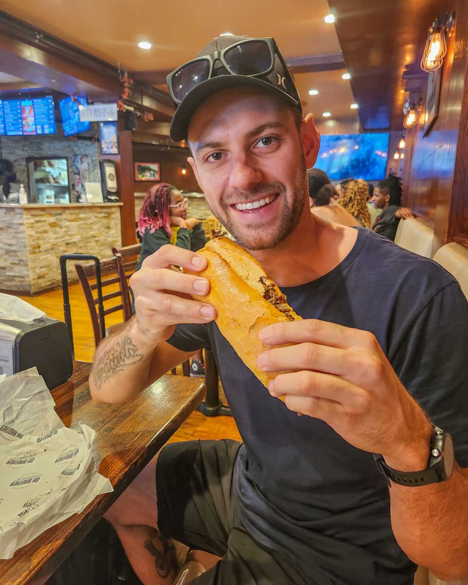 Daniel bites into a cheese steak in Oh Brother Philly 
